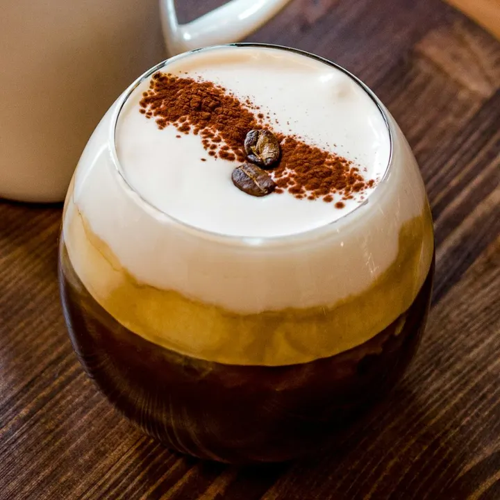 An iced coffee topped with cream, cocoa and coffee beans